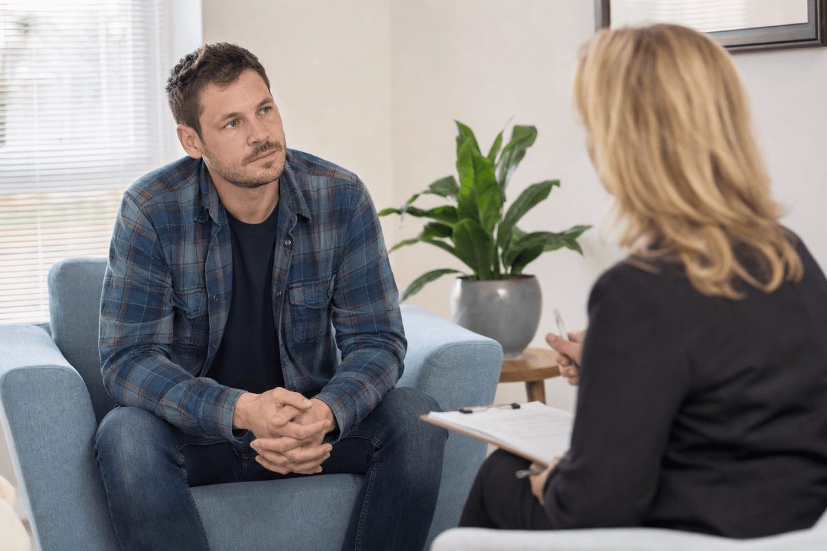 A person sitting with a clinician during a calm consultation in a sunlit treatment room