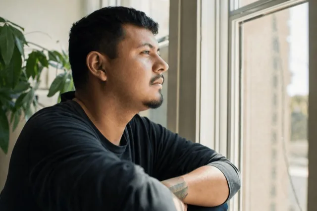A person sitting thoughtfully by a window in soft daylight during a quiet moment of reflection