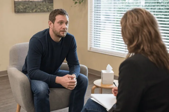 A person in a calm clinic consultation room talking with a clinician about opioid treatment options