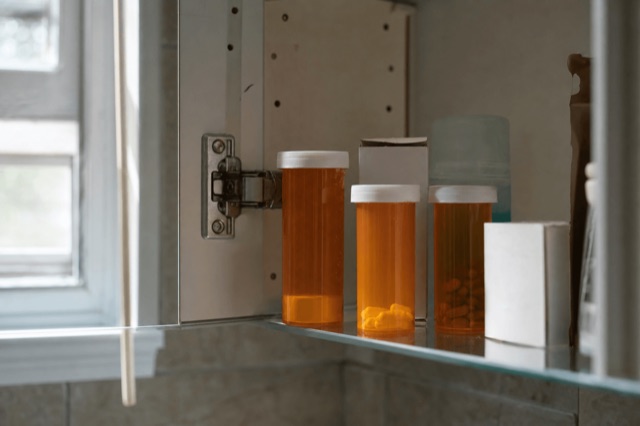 An open home medicine cabinet with prescription pill bottles on a bathroom shelf
