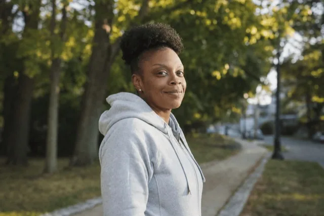 A person standing outdoors in soft morning light, looking calm and reflective during recovery
