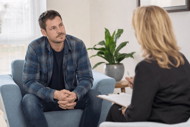 A person sitting with a clinician during a calm consultation in a sunlit treatment room