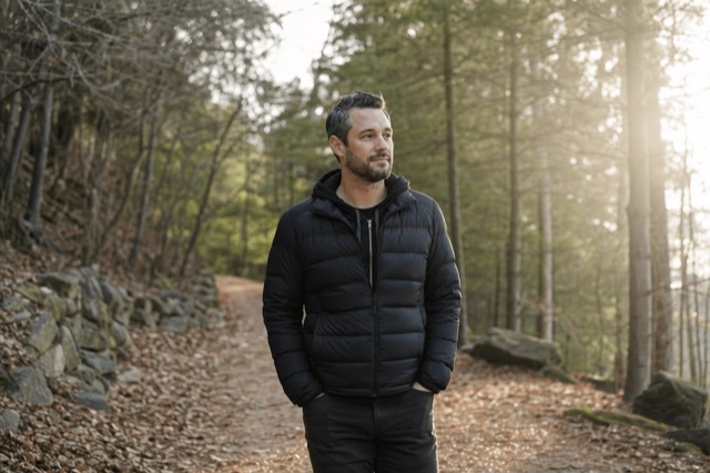 A person in recovery walking a quiet wooded path in soft morning light