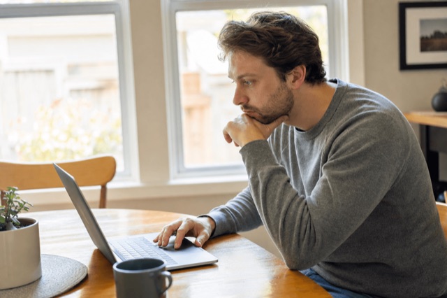 A person searching for nearby addiction treatment options on a laptop in a calm, sunlit room